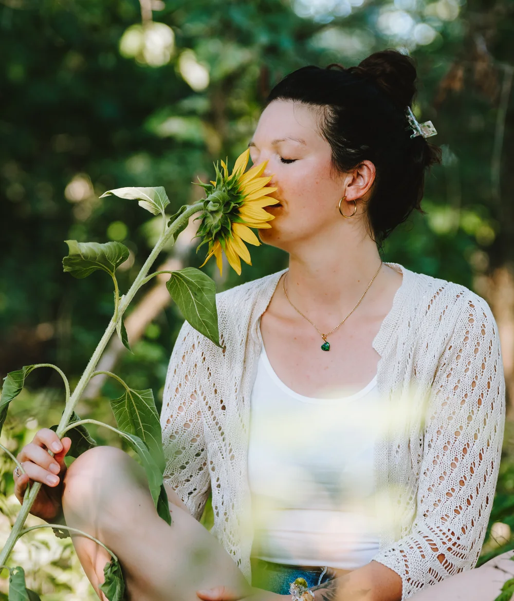 Vanessa Zach – Life & Impuls Coach – sitzend im Wald mit einer Sonnenblume